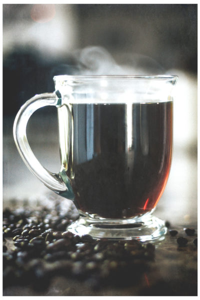 steaming cup of coffee with coffee beans